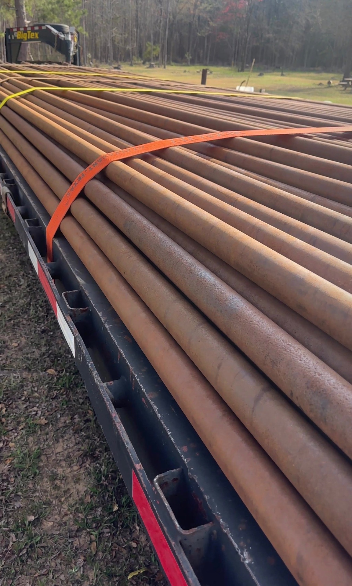 Flatbed loaded with bundled steel pipe strapped down for transport