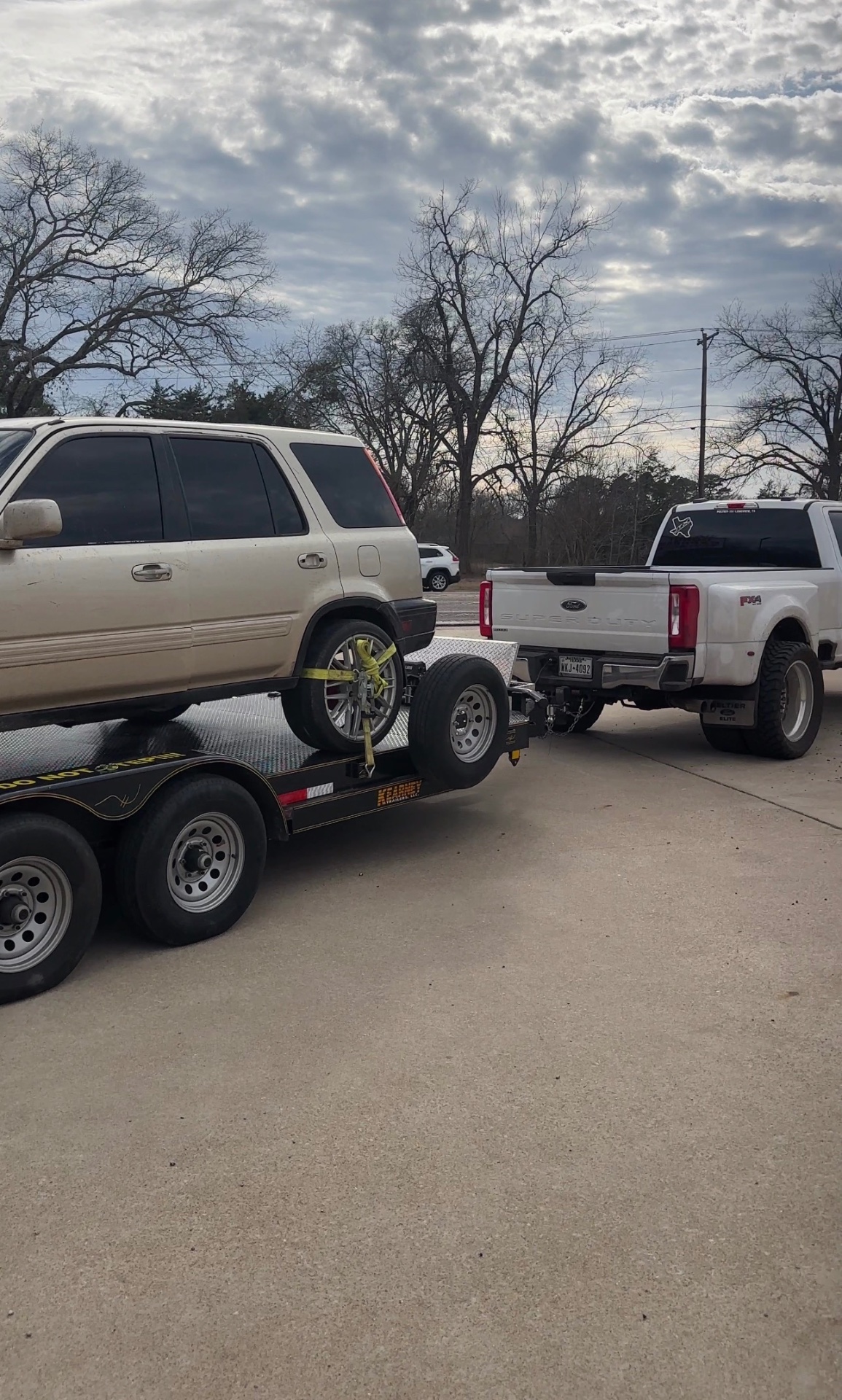 Honda CR-V loaded on a car hauler behind a Ford Super Duty
