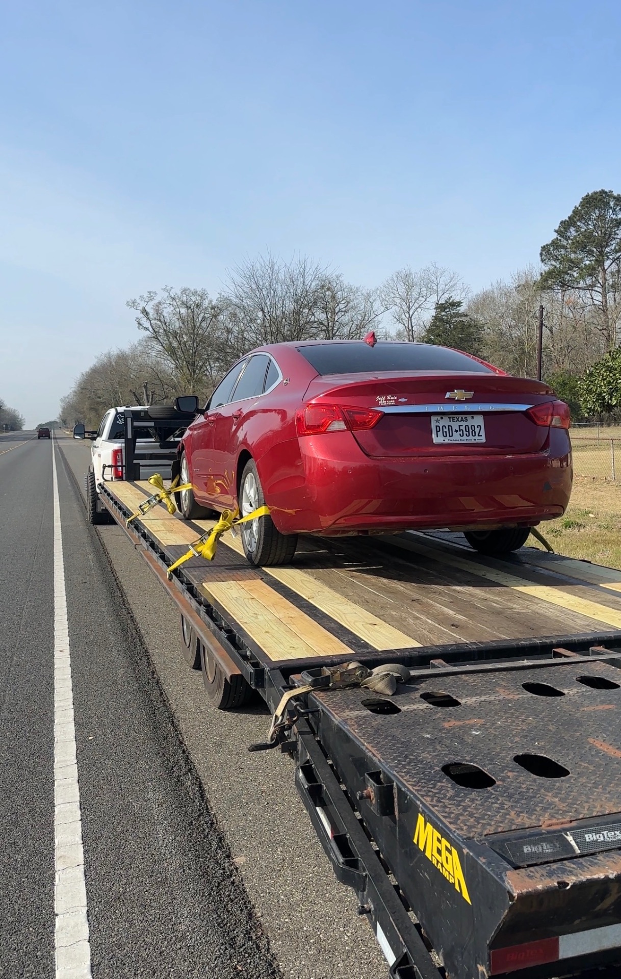 Flatbed semi truck hauling an excavator down a Texas highway